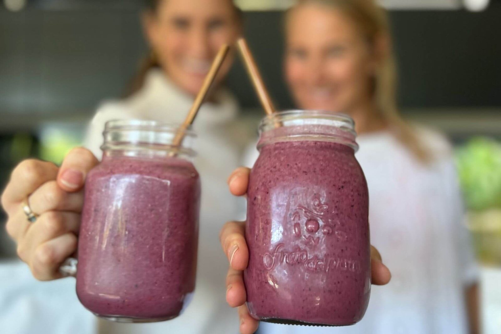 Anna and Em holding up protein berry smoothies