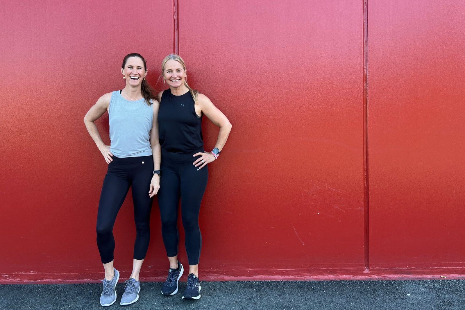 Anna and Em standing in front of a red wall