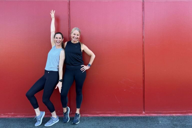 Anna and Em standing against a red wall