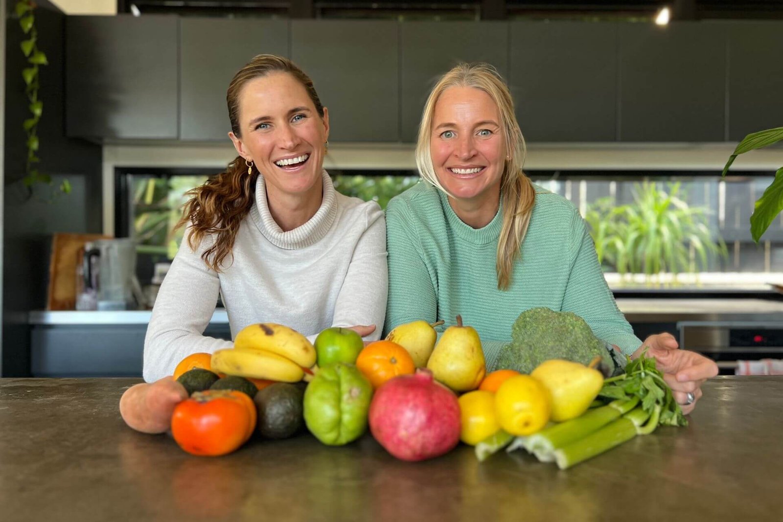 Anna and Em smiling in front of fruit and vegetables