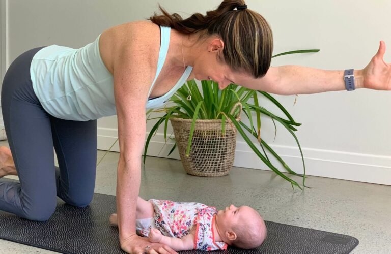 Em performing post natal exercise with baby on mat