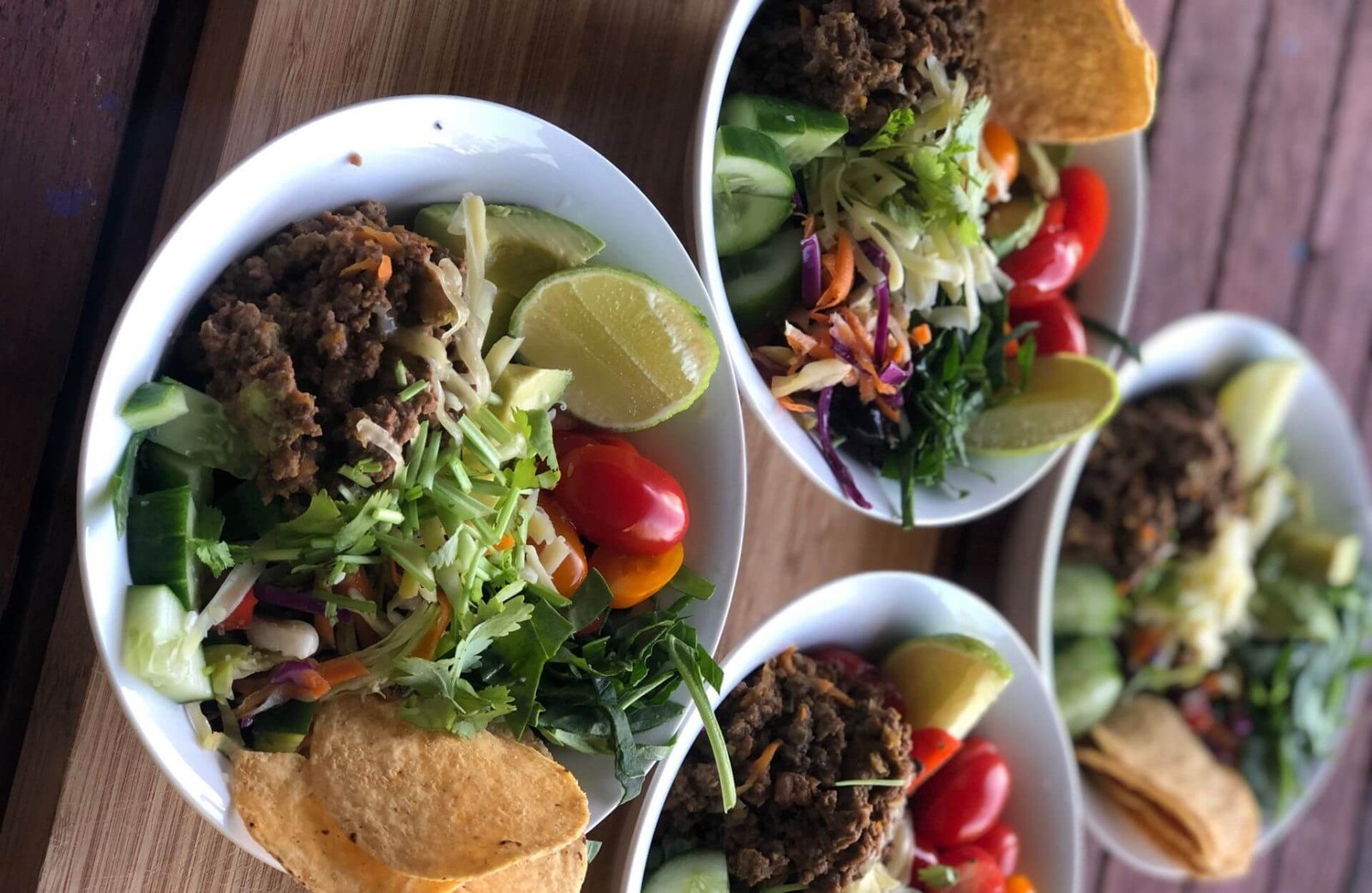 four taco bowls on outdoor table