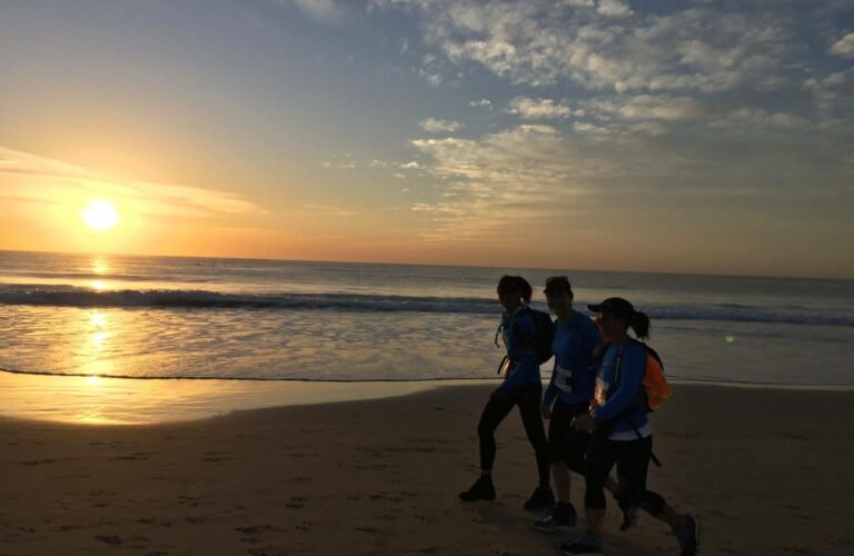 three women walking on beach at sunrise