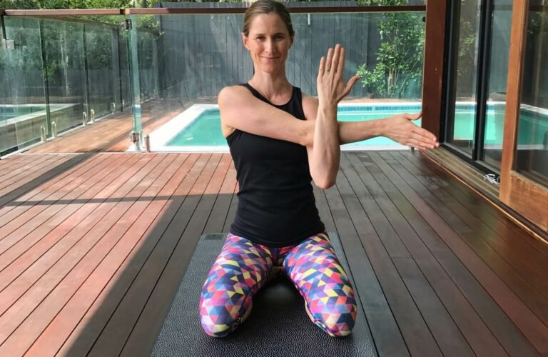 Em kneeling on the floor while performing a shoulder stretch