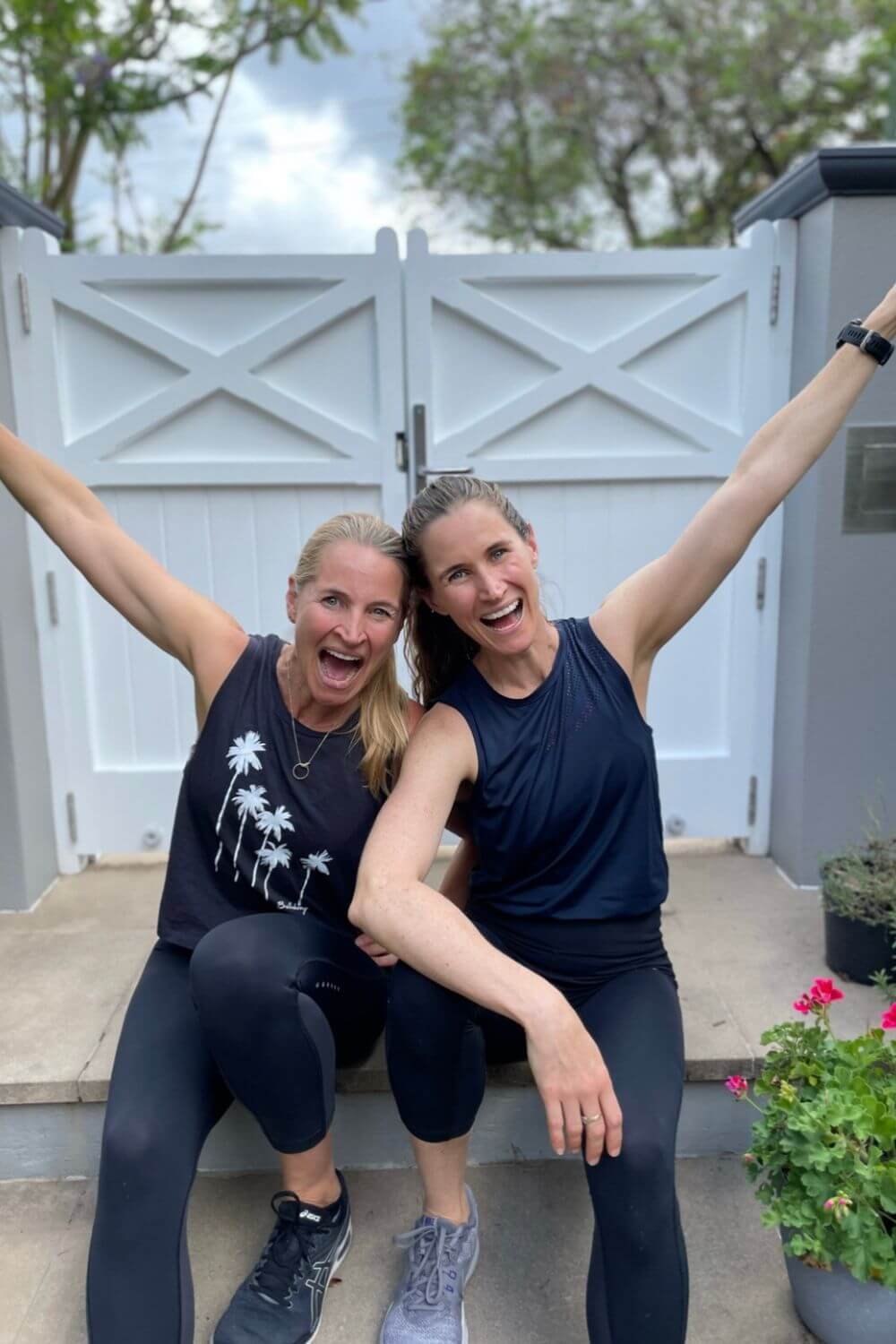 Anna and Em seated at front gate with arm in the air
